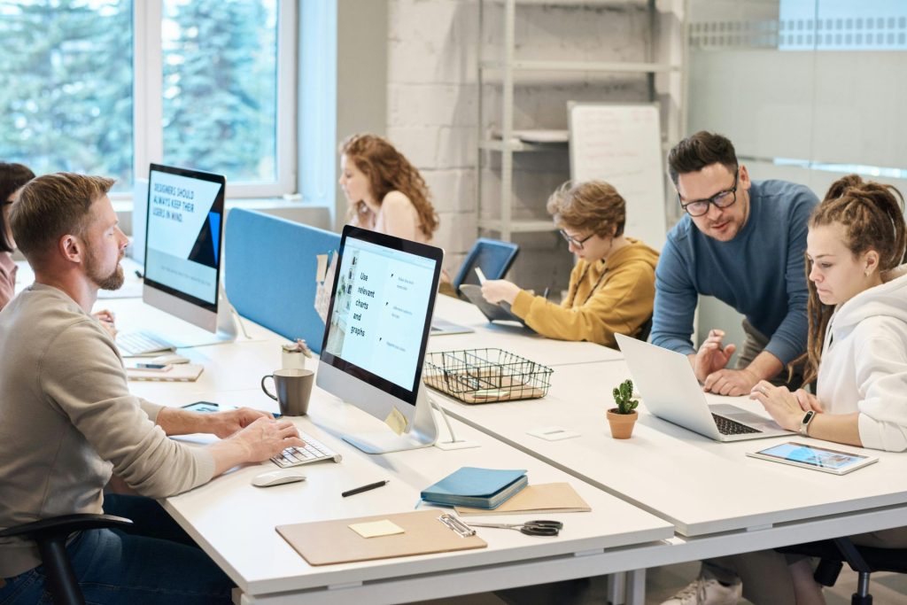 Teamzusammenarbeit in einer modernen Büroumgebung mit Computern und der Zusammenarbeit unterschiedlicher Mitarbeiter.