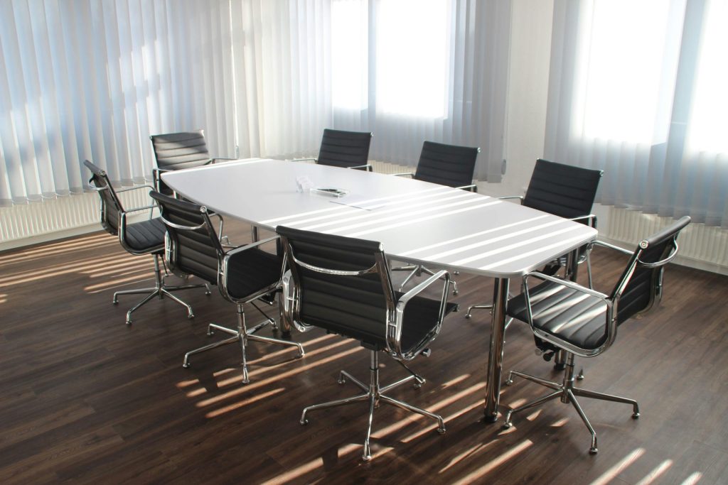 Moderner Büro-Besprechungsraum mit Designer-Stühlen, Tisch und großen Fenstern.